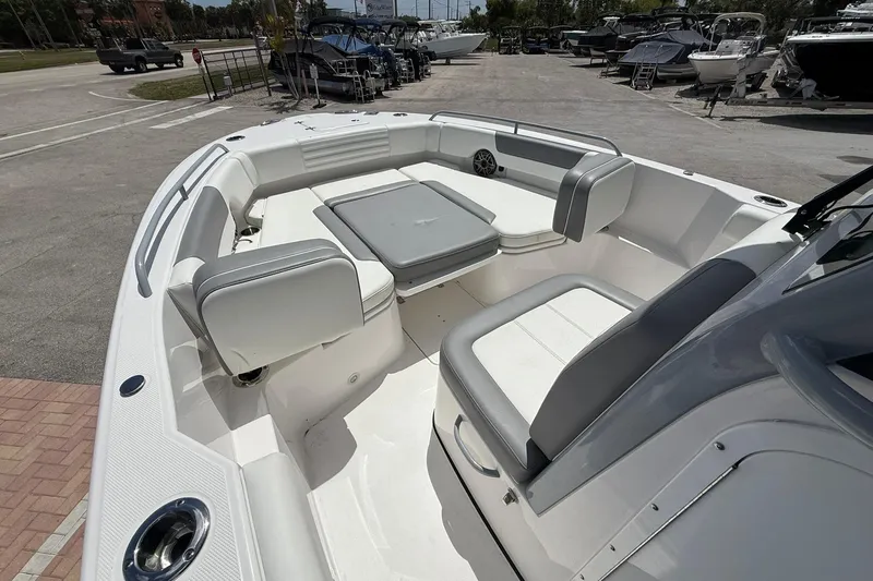 Slide: The Image of 2026 Edgewater 250CC boat interior with seating and table, parked in a marina. - 15