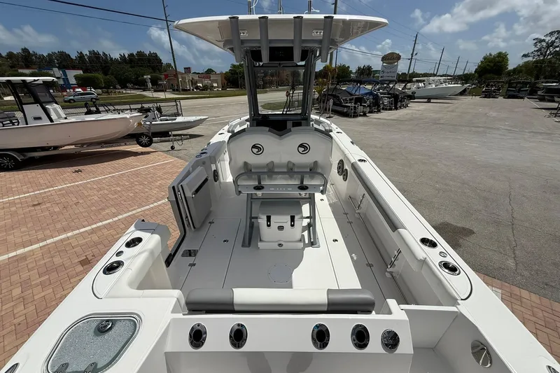 Slide: The Image of 2026 Edgewater 250CC boat interior with seating and storage, parked outdoors. - 8