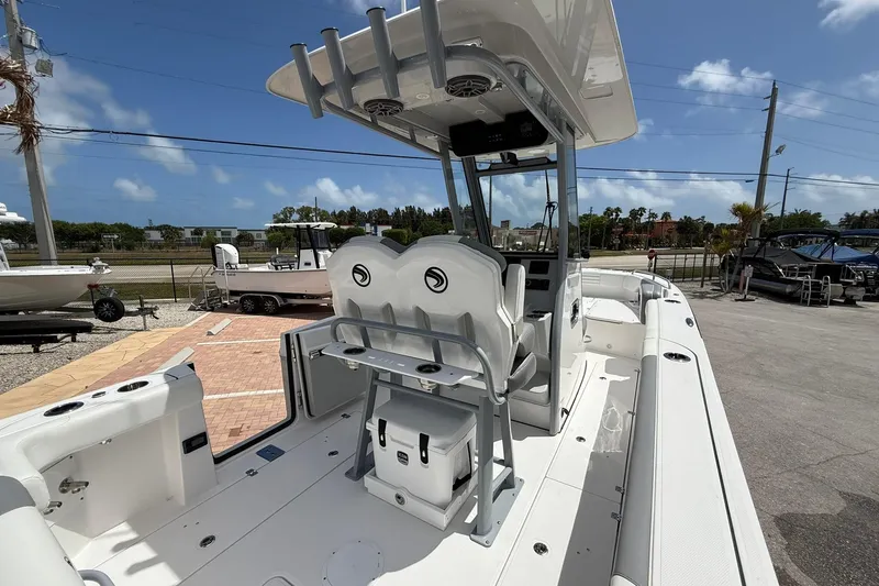 Slide: The Image of 2026 Edgewater 250CC boat interior with seating and console, parked outdoors under blue sky. - 9