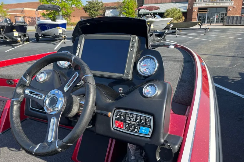 Slide: The Image of 2018 Nitro Z21 boat dashboard with steering wheel and control panel in a parking lot. - 5