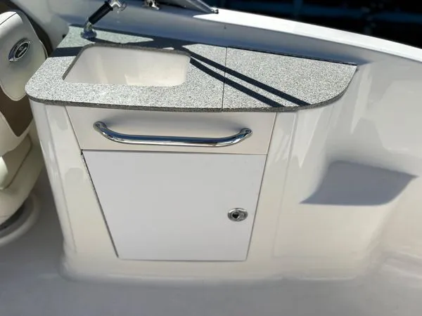 Slide: The Image of 2014 Chaparral 244 Sunesta boat kitchenette with sink and storage. - 25