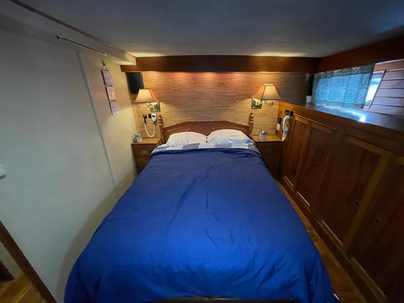 Slide: The Image of Cozy bedroom in 1972 Grand Banks Alaskan 55 yacht with blue bedding and wooden cabinetry. - 18