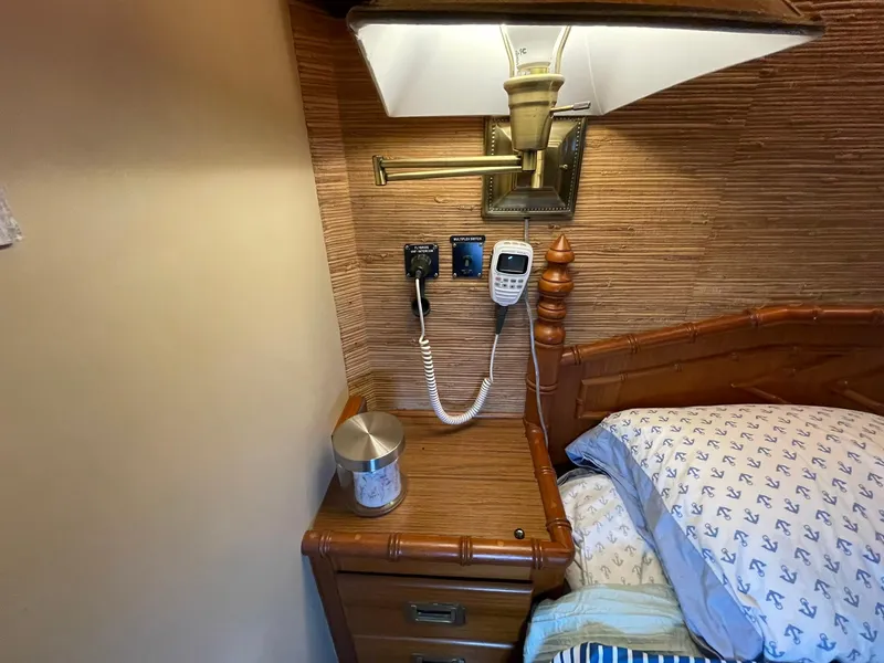 Slide: The Image of 1972 Grand Banks Alaskan 55 cabin interior with bed, nightstand, lamp, and nautical-themed bedding. - 19