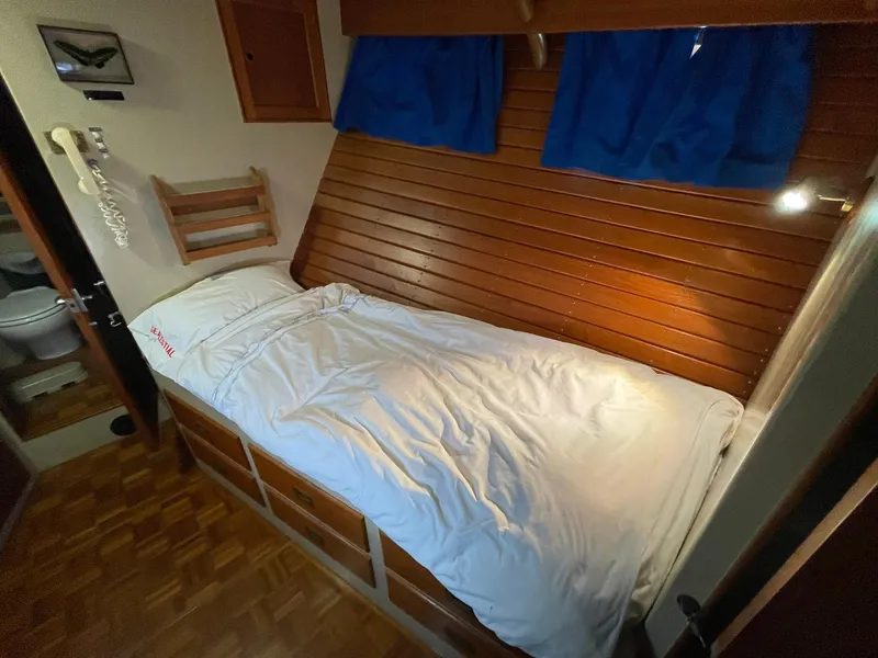 Slide: The Image of Cozy cabin bed in 1972 Grand Banks Alaskan 55 yacht with wooden paneling and blue curtains. - 30