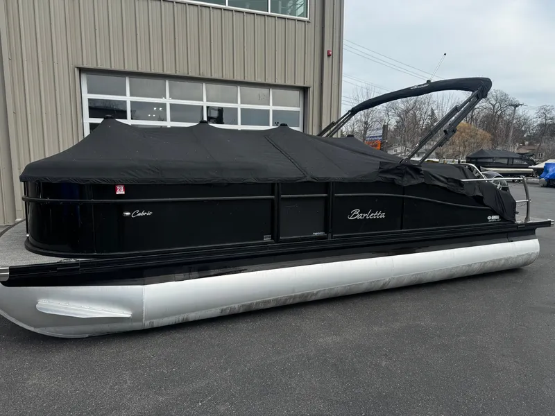 Slide: The Image of 2022 Barletta C22UC pontoon boat with black cover outside building. - 21