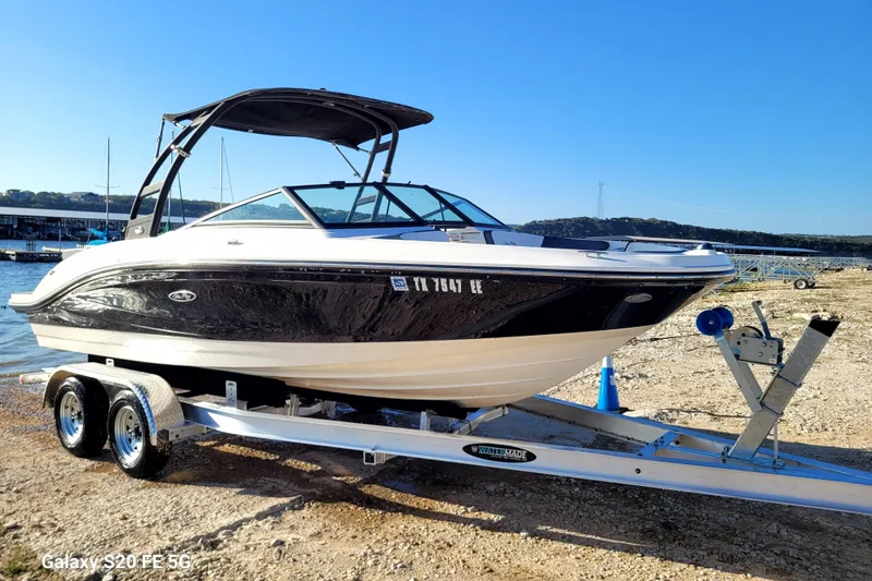 Slide: The Image of 2018 Sea Ray SPX 210 boat on trailer by lakeside, under clear blue sky. - 38