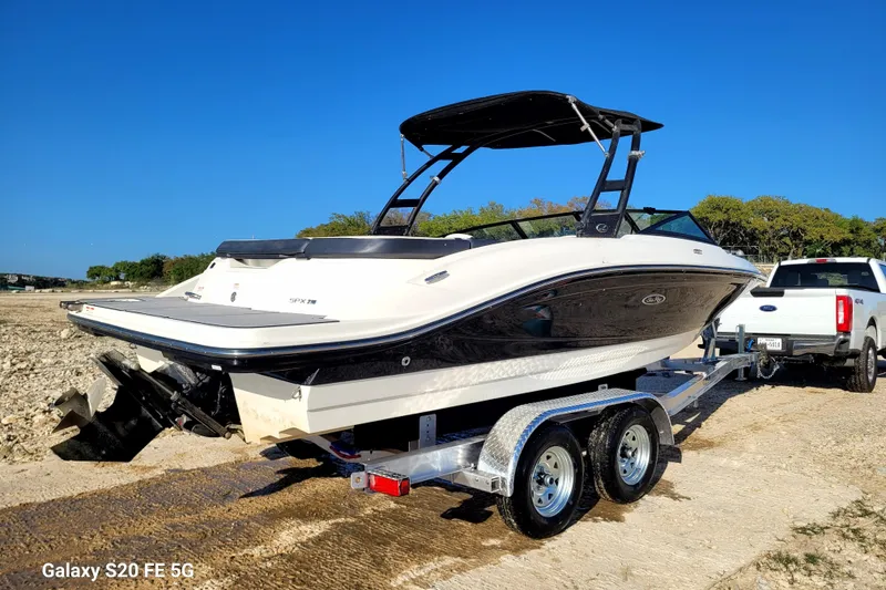 Slide: The Image of 2018 Sea Ray SPX 210 boat on trailer, parked near a white truck, under clear blue sky. - 40