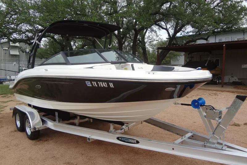 Slide: The Image of 2018 Sea Ray SPX 210 boat on trailer, parked outdoors with trees in background. - 6