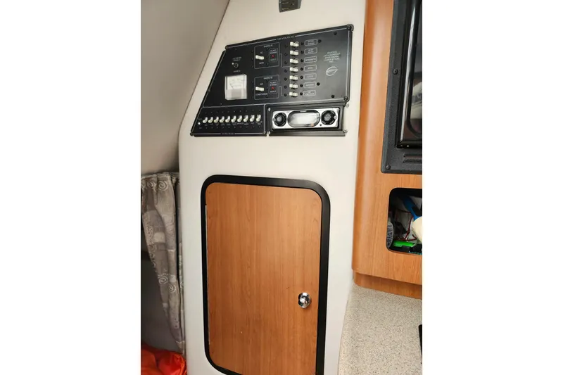 Slide: The Image of 2005 Crownline 275 CCR cabin interior with control panel and wooden cabinet door. - 12