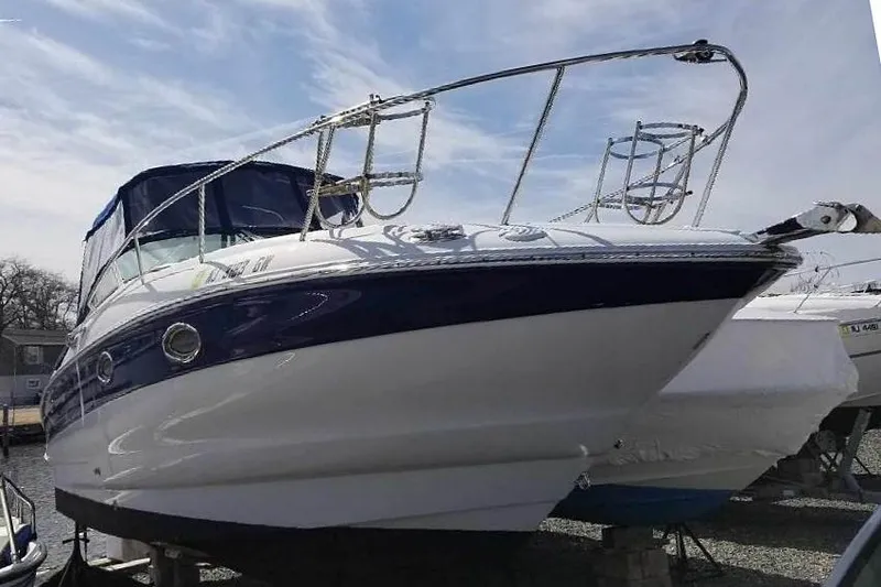Slide: The Image of 2005 Crownline 275 CCR boat with blue accents, docked under a clear sky. - 6