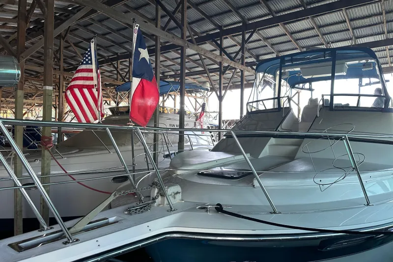 Slide: The Image of 1989 Carver 38 Santego yacht docked in covered marina with flags displayed. - 13