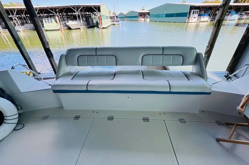 Slide: The Image of 1989 Carver 38 Santego boat interior with cushioned seating at a marina. - 23