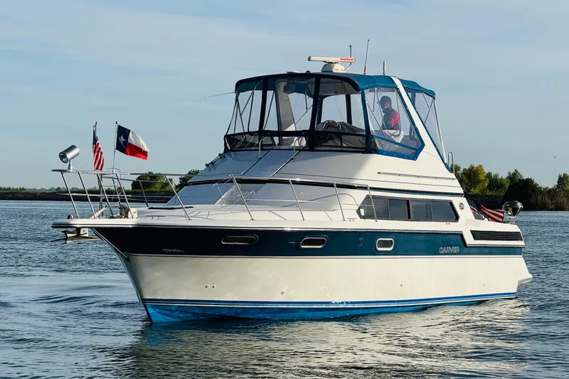Slide: The Image of 1989 Carver 38 Santego yacht cruising on calm waters with flags displayed. - 5