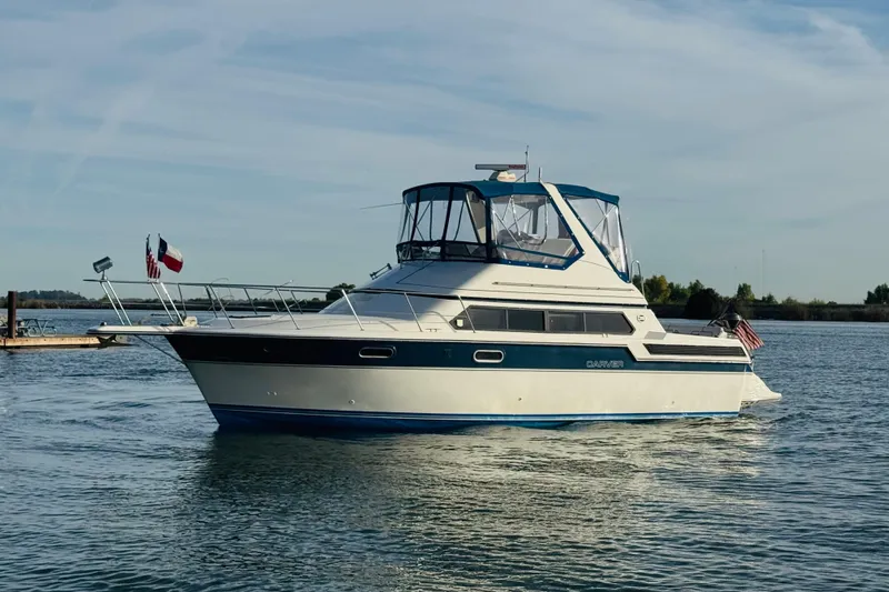 Slide: The Image of 1989 Carver 38 Santego yacht on calm water, featuring a sleek design and flags. - 6