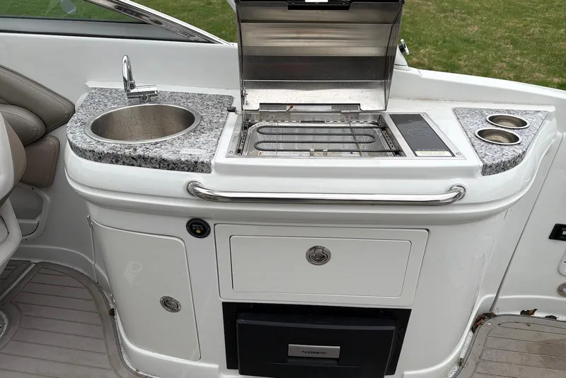 Slide: The Image of 2023 Crownline Eclipse E285 XS boat kitchenette with sink, grill, and storage. - 14