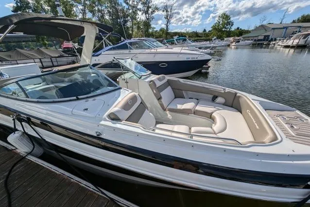 Slide: The Image of 2023 Crownline Eclipse E285 XS boat docked at marina, featuring sleek design and spacious seating. - 2