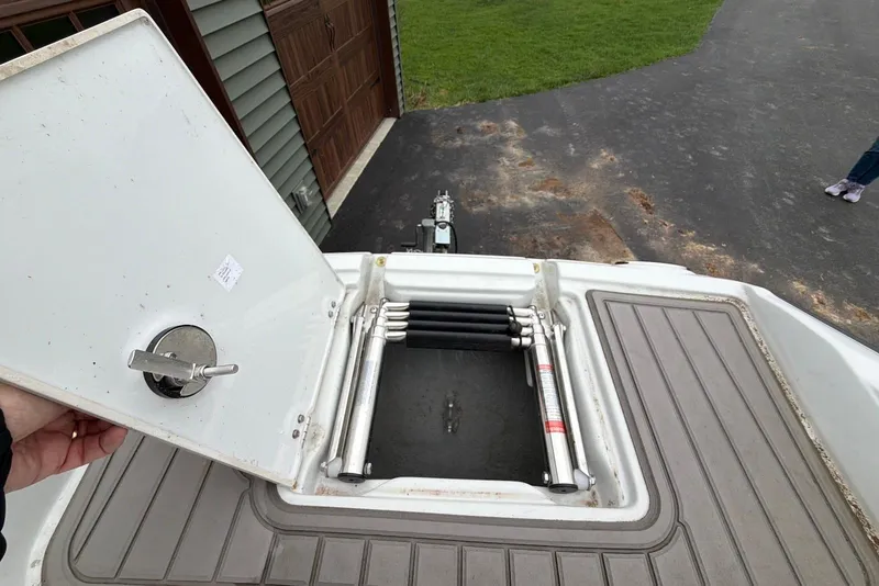 Slide: The Image of 2023 Crownline Eclipse E285 XS boat hatch with ladder, open on a driveway. - 20