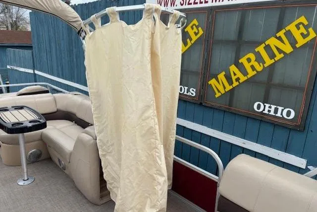 Slide: The Image of 2019 Sun Tracker SportFish 22 DLX pontoon boat with beige seating and privacy curtain. - 20