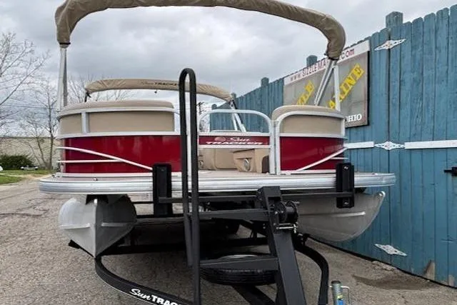 Slide: The Image of 2019 Sun Tracker SportFish 22 DLX pontoon boat on trailer, parked near blue fence. - 3