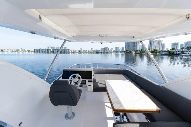 Slide: The Image of 2023 Azimut Fly 50 yacht interior with steering wheel and seating area, overlooking waterfront cityscape. - 42