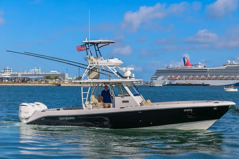 Slide: The Image of 2017 Everglades 355 Center Console boat cruising near a large cruise ship in a harbor. - 10