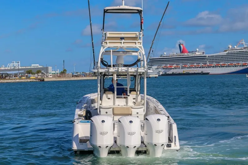 Slide: The Image of 2017 Everglades 355 Center Console boat with triple engines in a harbor, cruise ship in background. - 16