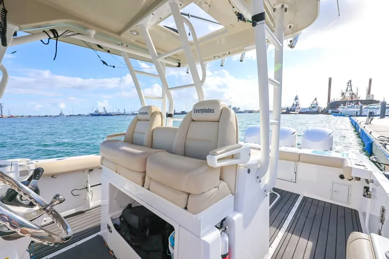 Slide: The Image of 2017 Everglades 355 Center Console boat interior with beige seating, docked by the sea. - 40