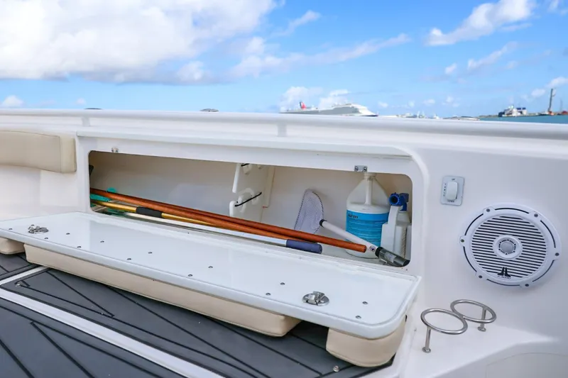 Slide: The Image of Storage compartment on 2017 Everglades 355 Center Console boat, featuring cleaning supplies and tools. - 59