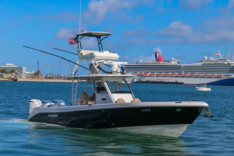Slide: The Image of 2017 Everglades 355 Center Console boat cruising in harbor with cruise ships in background. - 9