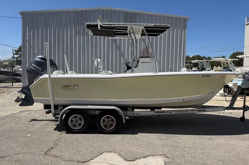 Slide: The Image of 2017 Sea Hunt Triton 210 boat on trailer, parked outdoors near a metal building. - 10