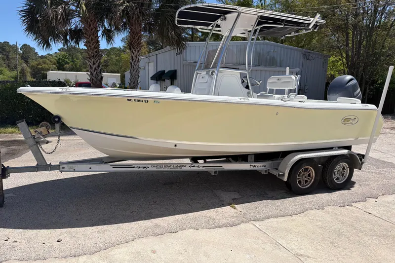 Slide: The Image of 2017 Sea Hunt Triton 210 boat on trailer, parked outdoors near palm trees. - 13