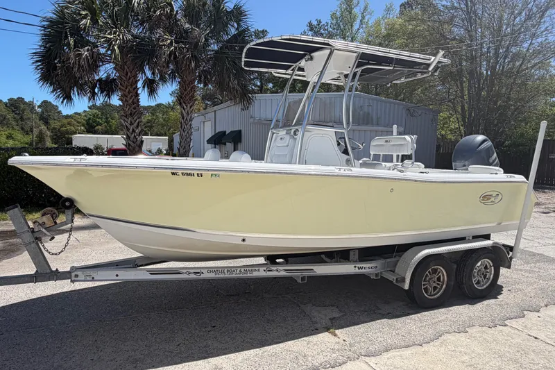 Slide: The Image of 2017 Sea Hunt Triton 210 boat on trailer, parked outdoors near palm trees. - 3