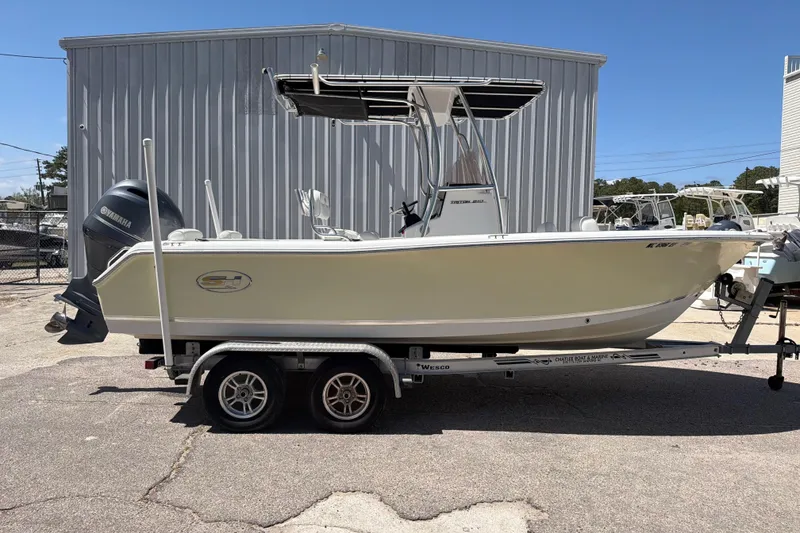 Slide: The Image of 2017 Sea Hunt Triton 210 boat on trailer, parked outdoors near a metal building. - 9