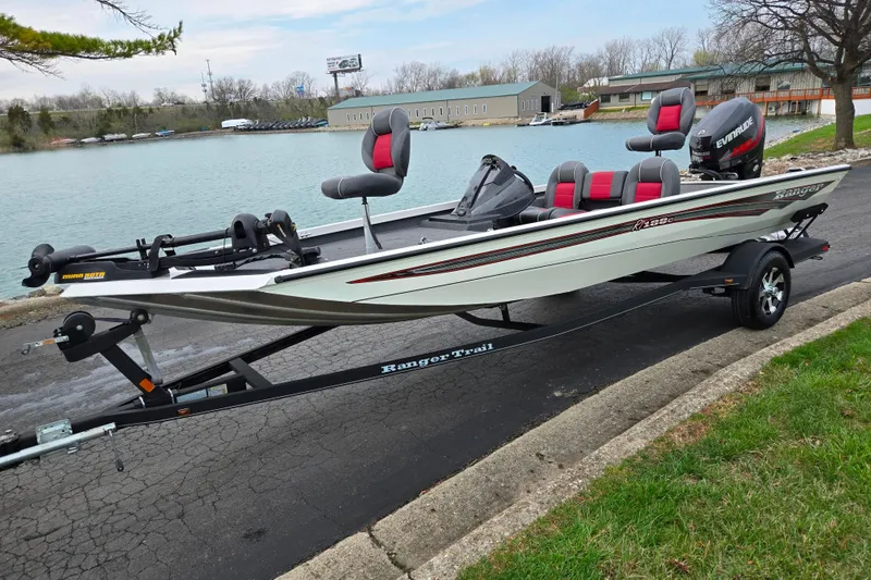 Slide: The Image of 2018 Ranger RT188C fishing boat on trailer by a lake, featuring red and gray seating. - 8