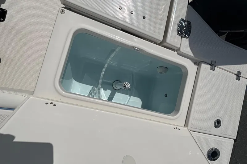 Slide: The Image of Livewell compartment on 2025 Robalo 246 Cayman boat, featuring white interior and secure latches. - 12