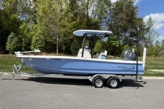 Slide: The Image of 2025 Robalo 246 Cayman boat on trailer, parked outdoors with trees in background. - 3