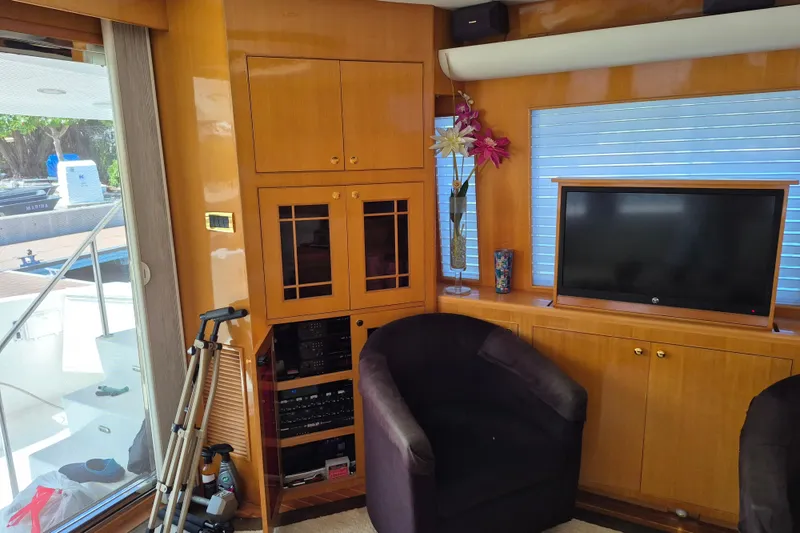 Slide: The Image of Interior of a 2006 Altima Flybridge yacht with wooden cabinets, TV, and seating area. - 10
