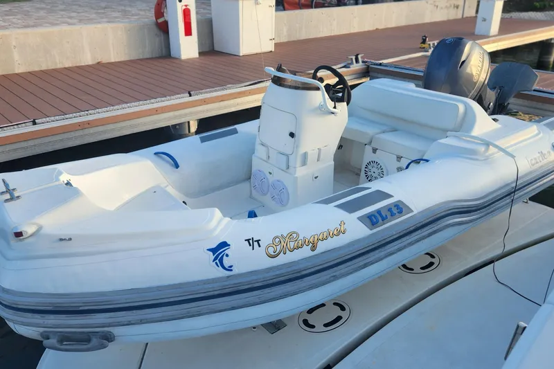 Slide: The Image of White inflatable boat docked, featuring a Yamaha engine, labeled "Margaret" and "DL 13." - 18