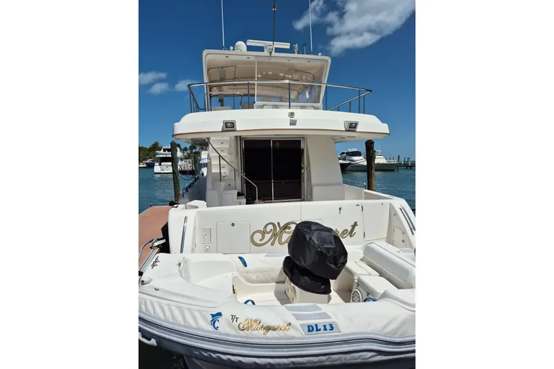 Slide: The Image of 2006 Altima Flybridge yacht docked at marina, featuring spacious deck and clear blue sky. - 5