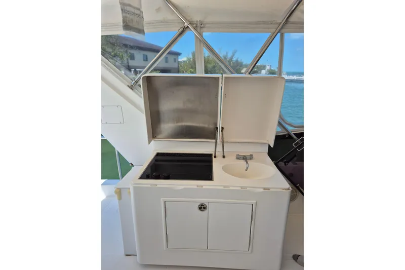 Slide: The Image of 2006 Altima Flybridge yacht kitchenette with sink and stove, featuring outdoor views. - 9