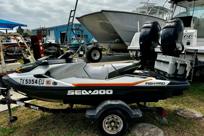 Slide: The Image of 2019 Sea-Doo FishPro 155 on trailer, parked near boats, showcasing sleek design and features. - 2