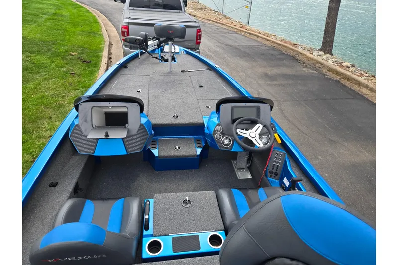 Slide: The Image of 2022 Vexus AVX2080 boat interior with blue accents, parked near a lake. - 11