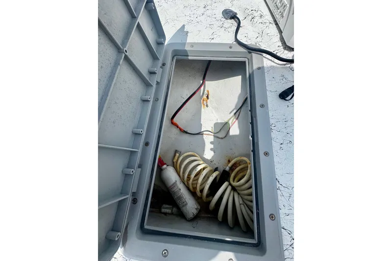 Slide: The Image of Open storage compartment on a 2007 Haynie 23 Bigfoot boat, containing coiled hose and wiring. - 23