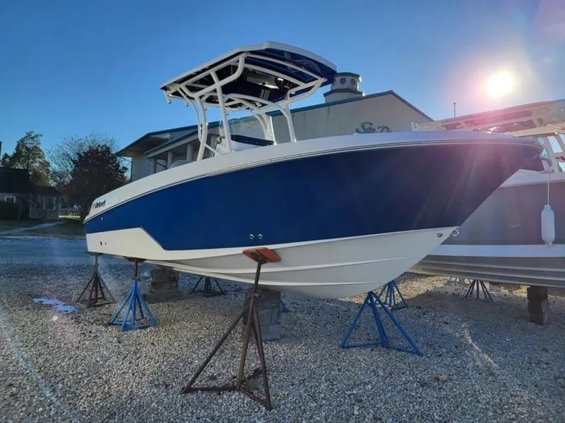 Slide: The Image of 2023 Wellcraft 222 Fisherman boat on stands, blue and white hull, sunny day. - 2