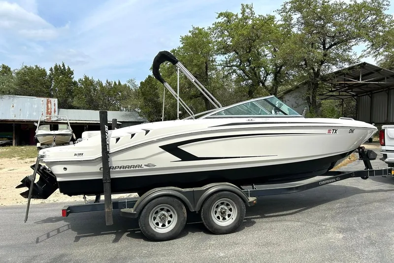 Slide: The Image of 2016 Chaparral 21 H2O Sport boat on trailer, parked outdoors near trees and buildings. - 13