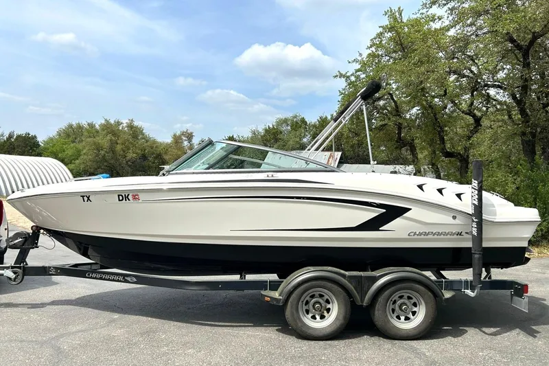 Slide: The Image of 2016 Chaparral 21 H2O Sport boat on trailer, parked outdoors under a clear sky. - 16