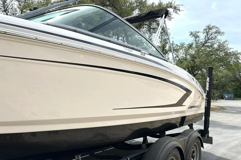 Slide: The Image of 2016 Chaparral 21 H2O Sport boat on trailer, side view with trees in background. - 17