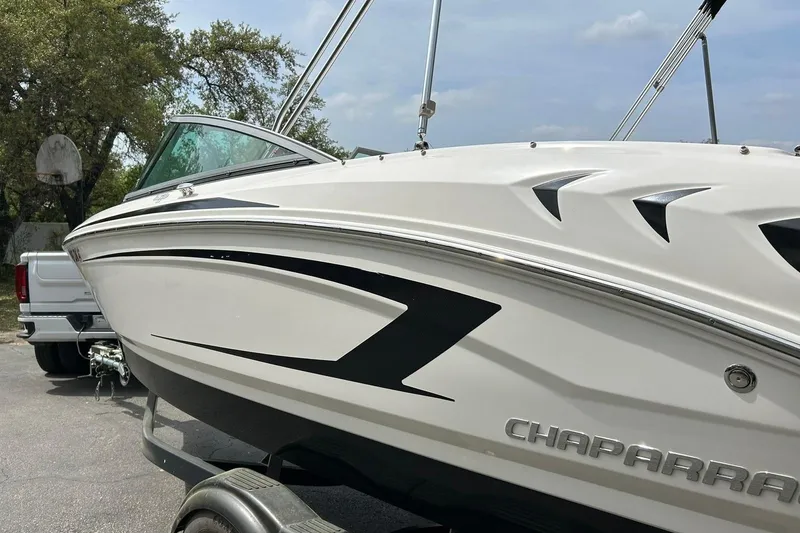 Slide: The Image of 2016 Chaparral 21 H2O Sport boat on trailer, sleek design, parked outdoors. - 21