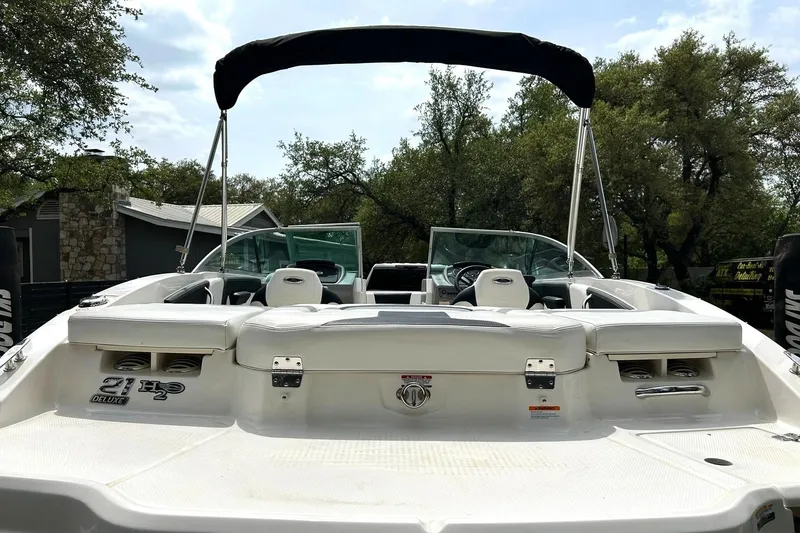 Slide: The Image of 2016 Chaparral 21 H2O Sport boat with canopy, rear seating, and lush greenery background. - 23