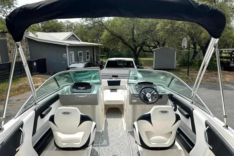Slide: The Image of 2016 Chaparral 21 H2O Sport boat interior with seating and steering wheel, parked outdoors. - 24